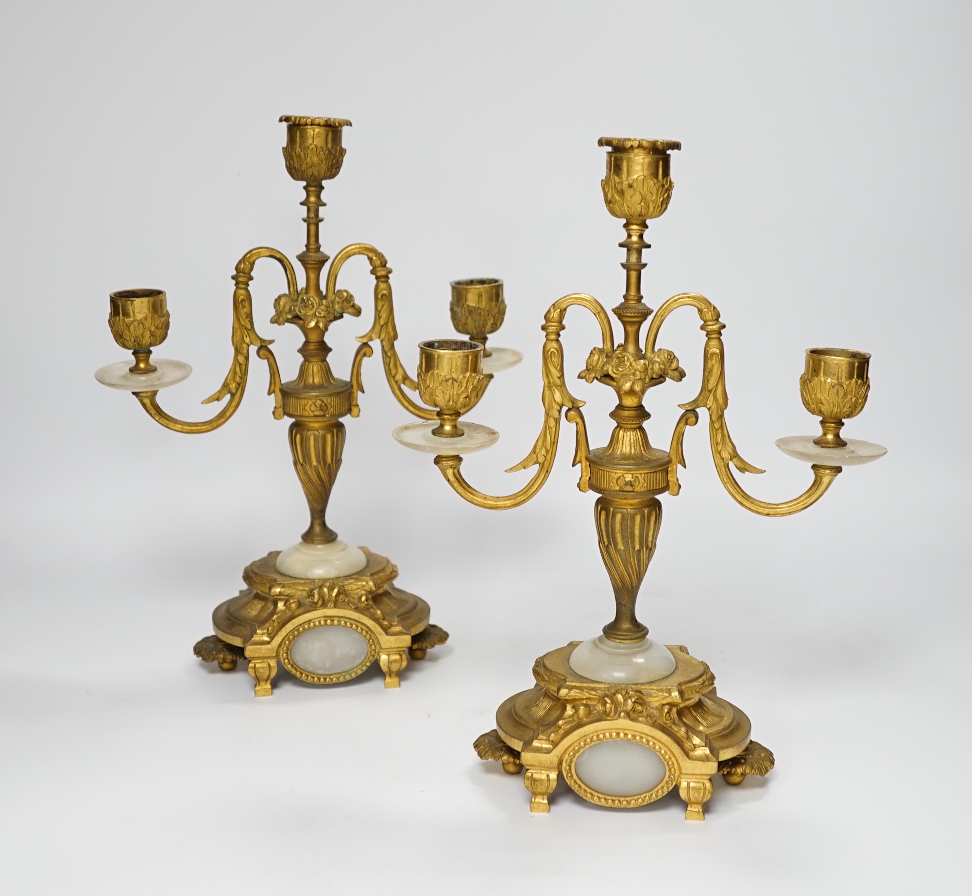 A pair of Louis XVI style ormolu and white onyx three branch candelabra, 29cm high